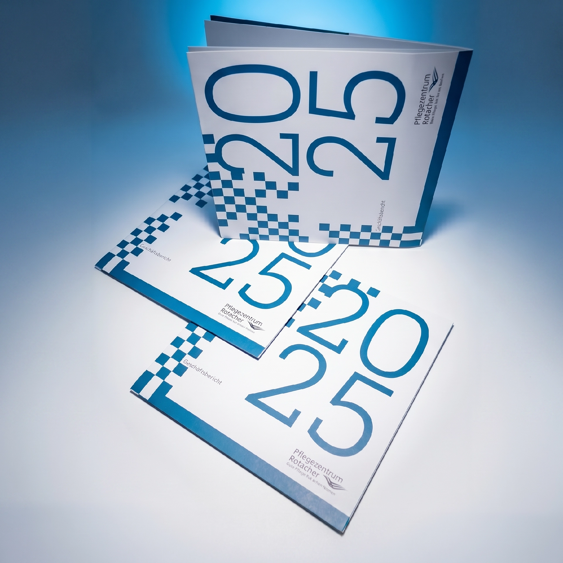 Geschäftsbericht 2025 Pflegezentrum Rotacher, Cover-Stapel mit blauer Pixel-Optik im Studio
